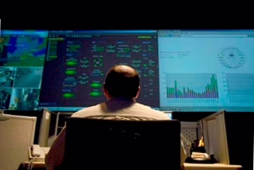 Network operations wall with multiple monitoring screens and dashboards